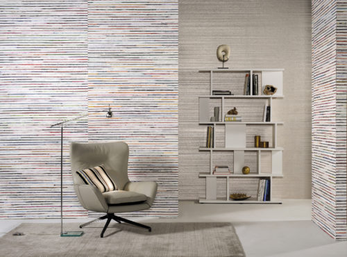 A peacefull room with earth tones: grey plain wallcovering with foil on the far wall. A modern bookshelf brings the room to life. Natural bakbak and recycled sari silk Seraya wallcovering on the other walls. Inviting lounge chair and reading light.