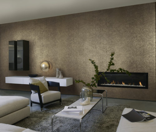 Tactile living room with contemporary fireplace. We see the white leather sofa, black and white consoles on the wall and outstanding golden sfere lamp. The wall is dressed in brown and gold wallcovering by Omexco.