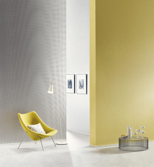 Lemon coloured wall with mica stones. Yellow lounge chair. On the far wall satin silver mica wallcovering with embossed square.