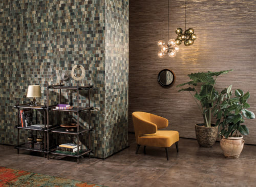 Tactile decor in earthly colours: green bakbak wallcovering, ocre chair, terracotta plant pots. Two pendant lamps bring out the gold shine in the raffia wallcovering on the far wall.