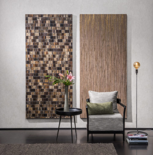 Plain wallcovering is the canvas for two outstanding wallcoverings: a brown bakbak and a golden raffia. A chair stands proudly in front of the wall art.