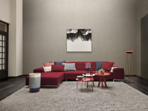 Interesting living room. Tall wall with silver mica wallcovering. Impressive black and white artwork. Red furniture adding to the wow factor.