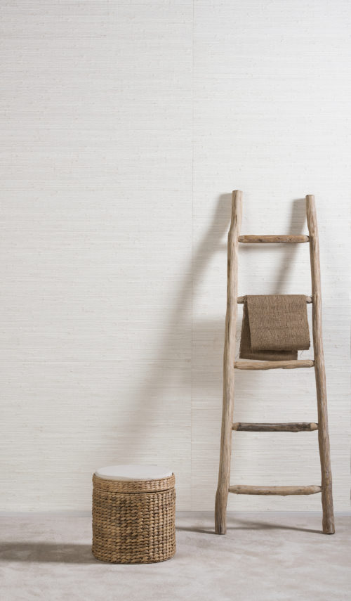 Cute antique ladder leaning against bamboo wallcovering from the Shades of Pale range. Rotan box.