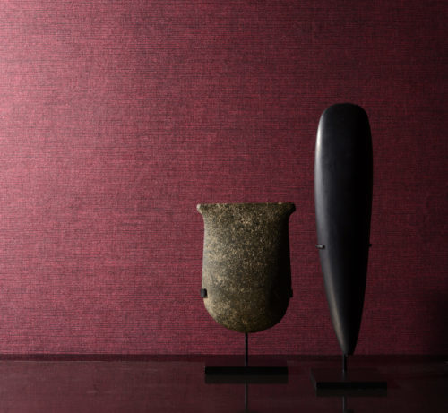 Red non-woven wallcovering on the wall. It looks like sisal wallcovering, but with better technical properties. Two african statues.