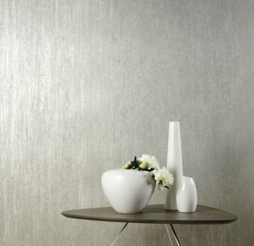 Pristine decor of silver wallcovering, different white vases and white flowers.