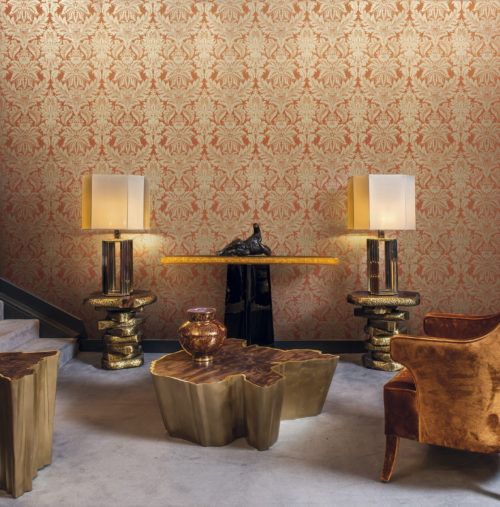 Tactile room with brown armchair and golden lamps and centre table. Eyecatching gold and orange damast wallcovering by Gala.