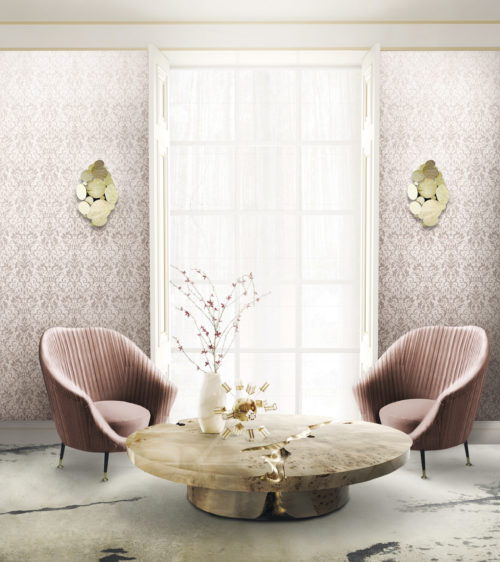 Well lit living room with large window. On both sides of the window pink Gala wallcovering with a foil damask, golden wall lamps. called Newton. Pink velvet chairs by Koket, empire center table.