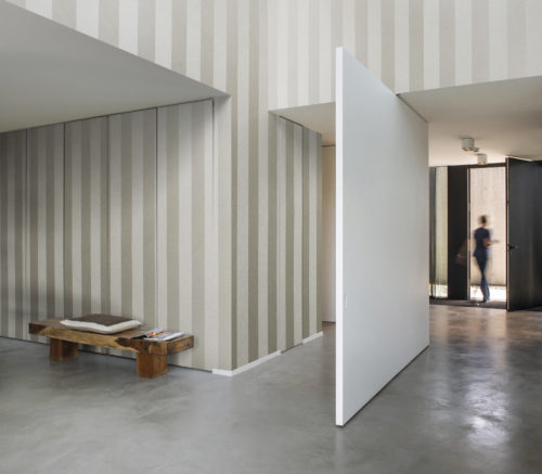 Contemporary hallway with pivoting white door. Behind the Omexco Portfolio wallcovering, cupboard doors are hiding.