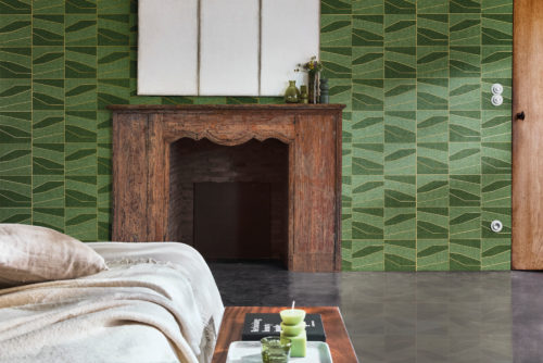 This charming bedroom highlights the OAS233 reference, titled Domino, from Omexco’s Oase collection. The wallcovering, crafted from a patchwork of paperweave, showcases geometric shapes resting upon a metallic backing, available in gold or silver. The rich green tones and structured lines create a harmonious balance between nature and modernity, perfectly complementing the rustic wooden fireplace. Soft, neutral-toned bedding and a wooden bedside table enhance the warmth of the space, while subtle green decorative accents tie the elements together, creating a serene and inviting atmosphere.