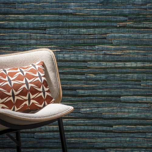 Outstanding waterlily wallcovering in dark green. In front of it a white chair with orange geometric pillow.