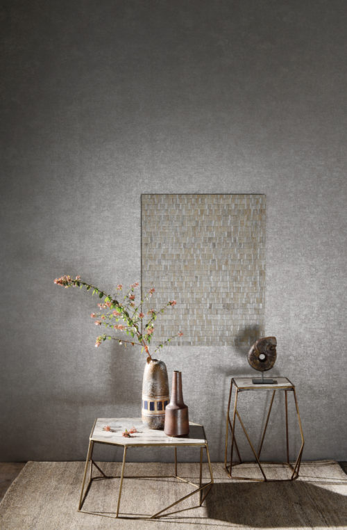 Silver room with pink detail from a branch of flowers in a multicoloured vase. The vase is standing on an assymetrical stool with golden legs. Waterlily wallcovering with silver touches on a frame.