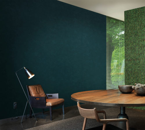 Living room with cosy leather chair and reading light. On the wall a deep green Kaleidoscope wallcovering.