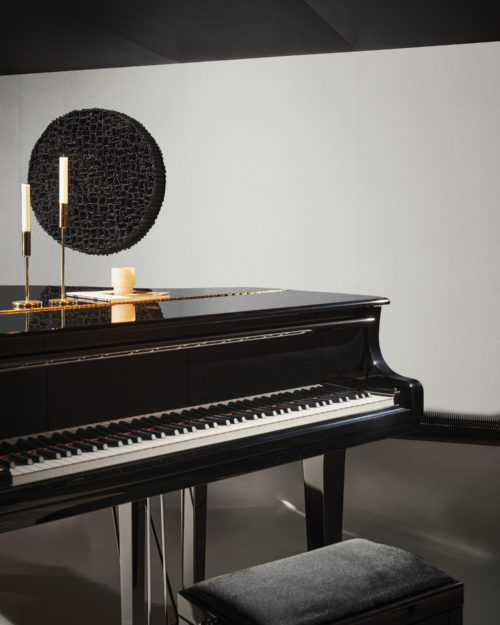 A sophisticated decor shot showcasing a black grand piano set against a sleek grey floor. The walls are adorned with Omexco's Silence wallcoverings in a soft light grey, adding both a touch of elegance and acoustic functionality to the space. This refined composition combines the timeless allure of a grand piano with the modern aesthetic of acoustic wallcoverings, creating a harmonious blend of style and functionality.