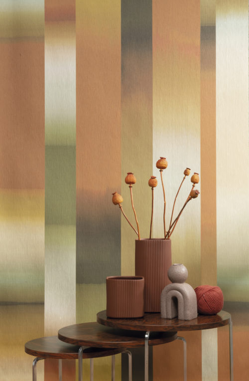 Closeup of a seventies inspired home decor. Bring the unique vibe from an incredible period in time back into your home with the "Time-lapse" wallcovering design from Omexco's "Atelier" collection. This modern rendition of an Ikat weaving show dynamic stripes in a color gradient of orange, green, brown, beige and yellow.