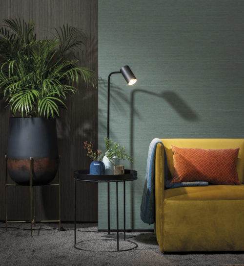 Decor with yellow velvet armchair, floor lamp, metal table. On the left a vase on handcrafted aluminium on iron statue.