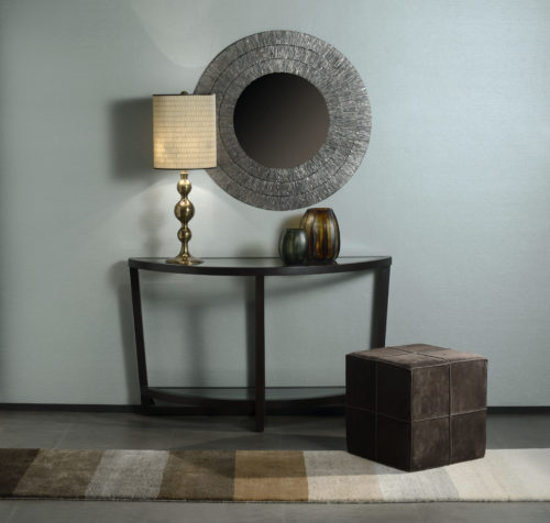 Peaceful decor with round mirror, leather poof and golden lamp. Behind it: light blue Infinity wallcoverings.