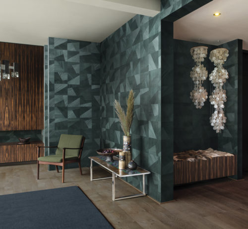 We see a stunning room with retro furniture and lamps. The perfect backdrop for the warm green and chic interlocking wood textures of the Dimensions design of the Omexco Sycamore collection.