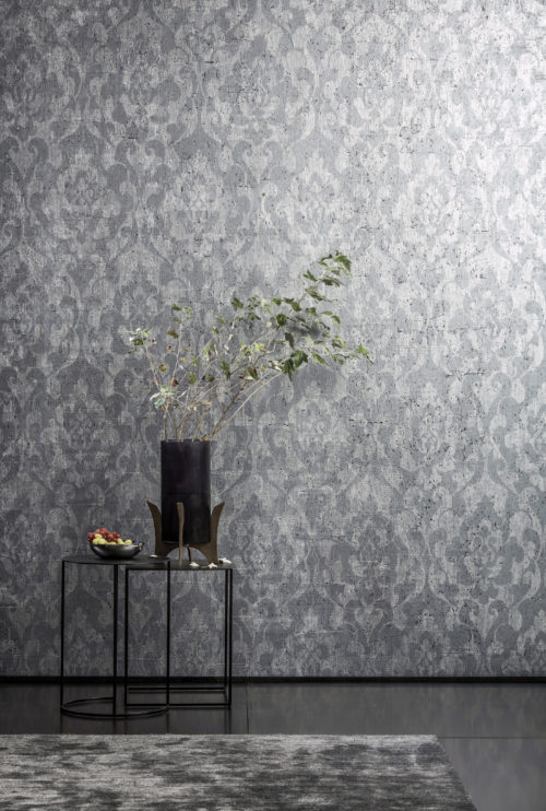 Wall with ANT404 Omexco wallcovering, black vase with branch on a table. There's fruit on the table. In front of the table is a soft grey carpet.