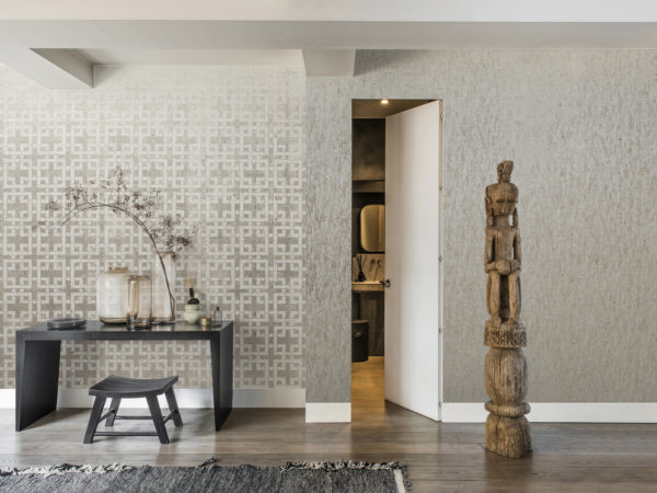 Asian inspired room with black table and wooden totem. Door to a little bathroom. Kork wallcovering on both walls.