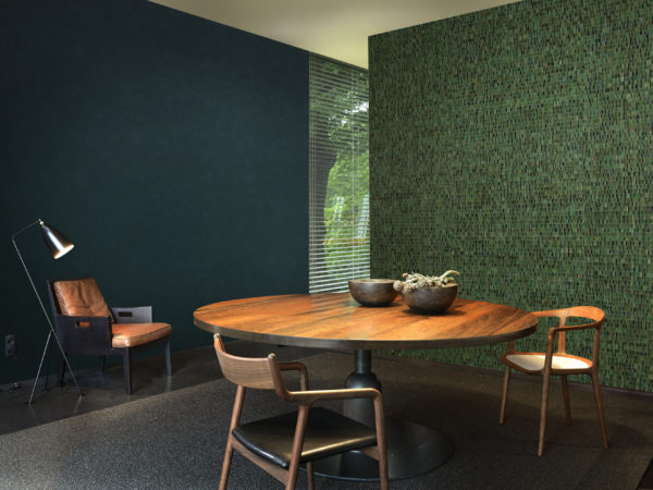 Living room with cosy leather chair and reading light. On the wall a deep green Nomad plain wallcovering. On the other wall a stunning green and black waterlily wallcovering.