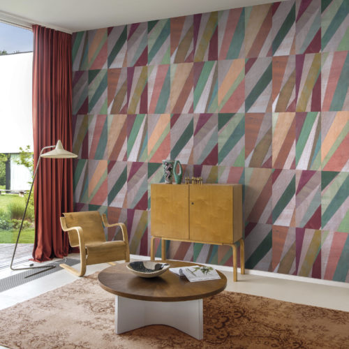 This playful living room with a bold statement wall brings you an instant feeling of happiness. The Joy wallcovering collection by Omexco is a true explosion of colour. A seductive conversation of jazzy geometrics and diagonal lines in vibrant shades of pink, green, orange and burgundy, reminiscent of a harlequin print.