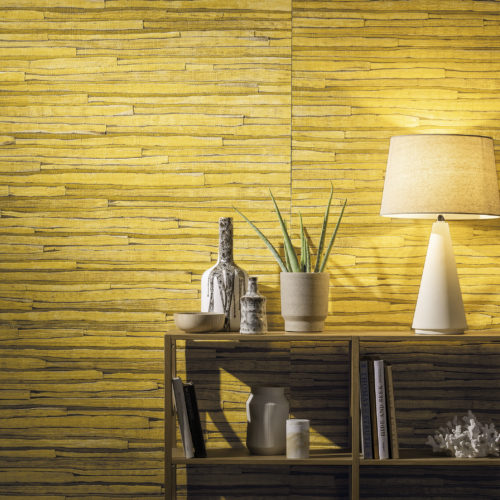 Close up of yellow waterlily wallcovering with wooden shelves. White lamp, books and a sea fossil.