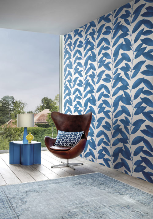 This image shows the Blooming Marvellous design from Omexco's wallcoverings collection Joy. The playful design with a pattern of blue leafs is the perfect backgrop for the iconic Egg chair designed by Arne Jacobsen. The large window adds brightness to the contemporary space.