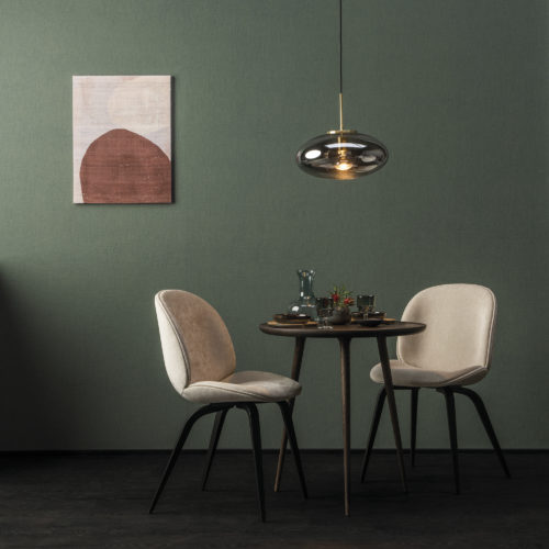 In this picture, we see a small dining table with two white chairs and a glass pendulum lamp. On the walls, Omexco's High Performance Texture wallcoverings are shown. We see the design 'linen' in moss green. It's the design that reminds us most of the local knowhow of working with Belgian linen.