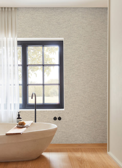 Example of a rustic modern bathroom with a freestanding bathtub, black taps, a window with garden view medium tone parquet floor. On the wall we see Omexco’s Belgian linen wallcoverings in off-white and light grey hues. Woven using the finest natural fibres and expert craftsmanship, each design of Omexco’s "Loom Stories" collection demonstrates its design studio’s commitment to create refinement and design elegance.