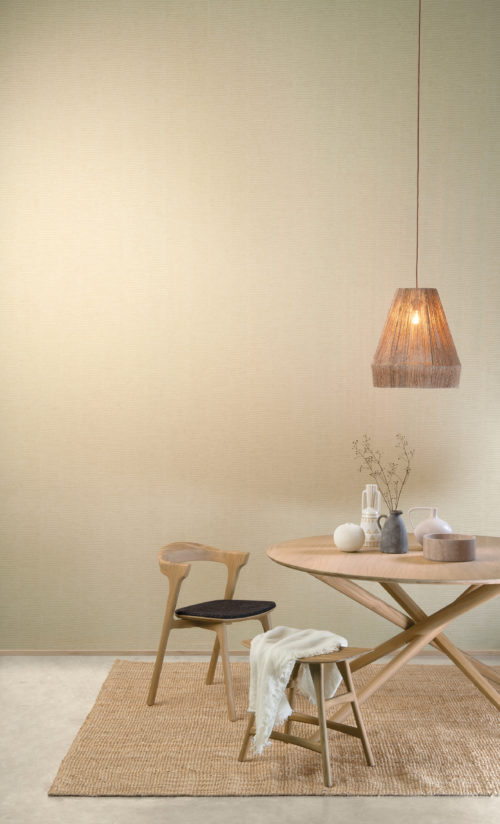The High Performance Patina Wallcovering collection by Omexco combines performance with sustainability and modern aesthetics. On the wall of this inviting dining room we see a beige print of vertical stripes combined with horizontal lines. The space is furnished with a Scandinavian style dining table and chairs, marked by a focus on clean, simple lines and minimalism.