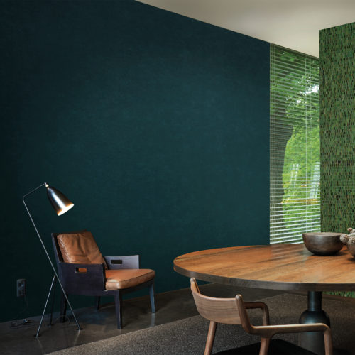 Living room with cosy leather chair and reading light. On the wall a deep green Kaleidoscope wallcovering.