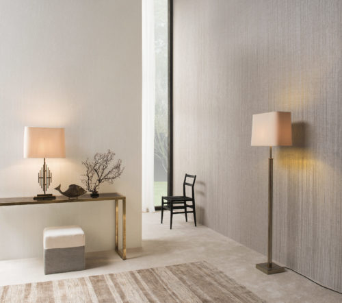 Cosy hallwall with two square lamps illuminating Shades of Pale crushed linen wallcovering. In the middle of the picture a black chair. Golden console with a black statue of a fish and a black branch.