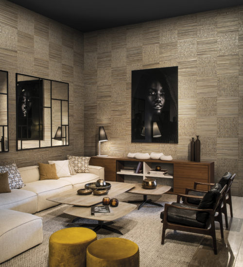 We see a modern interior in warm tones. The walls are luxuriously dressed in woven banana bark: the elegance of this natural material arises from the intricate craftsmanship of an experienced artisan who collects the banana bark from tropical climes.