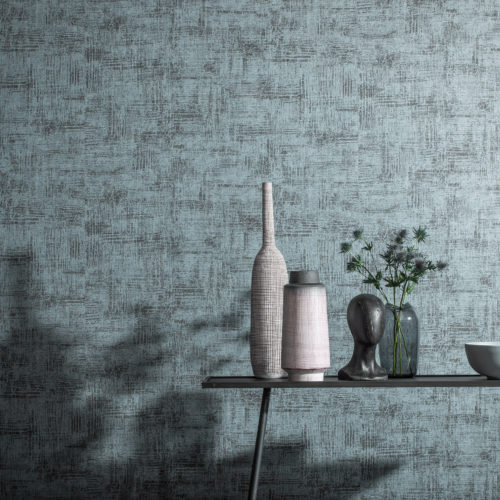 Ice blue interior picture with sleek table. On the table vases and a thistle. They cast a shadow on Aruba wallcoverings by Omexco.