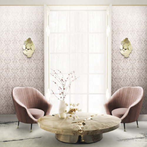 Well lit living room with large window. On both sides of the window pink Gala wallcovering with a foil damask, golden wall lamps. called Newton. Pink velvet chairs by Koket, empire center table.