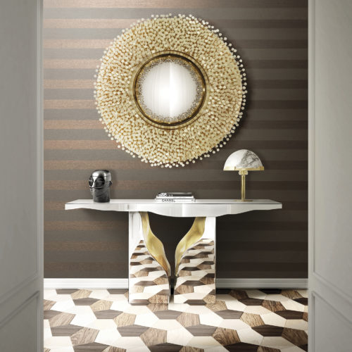 Picture of a chrome console that reflects the wooden inlay floor. Above it a round mirror with mother-of-pearl dots. Behind it horizontally installed Infinity striped wallcovering.
