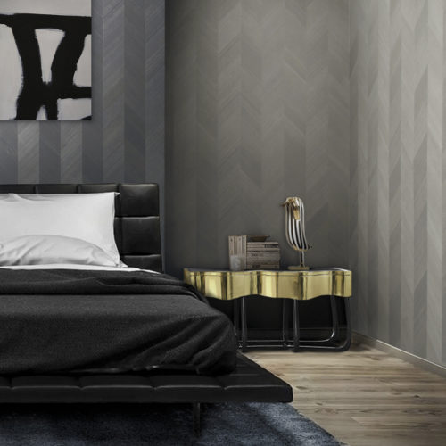 Bedroom with a black leather bed and golden nightstand. Abstrack black and white painting on the wall. Walls dressed in wood veneer wallcovering from the Omexco Infinity range.
