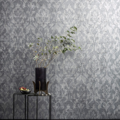 Wall with ANT404 Omexco wallcovering, black vase with branch on a table. There's fruit on the table. In front of the table is a soft grey carpet.