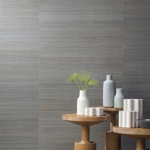 Sur cette photo, notre abaca très fin de la collection Seraya. Des fils d'abaca incroyablement fins tissés serrés pour un effet raffiné. Une version qui utilise des techniques modernes juxtaposées sur un support traditionnel. L'abaca gris est en contraste avec les vases pastel sur 3 tables rondes de différentes hauteurs.