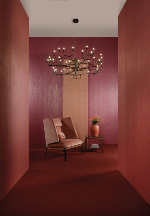 Revêtements muraux rouge cerise et orange vif. Impressionnante chaise en velours. Lustre noir avec des lumières en forme de bougies.