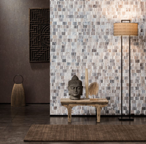 Nous présentons deux murs avec des revêtements muraux Omexco. L'un avec un bakbak à lavis blanc. En contraste, un uni brun foncé avec une structure sableuse. Détails asiatiques dans les accessoires.