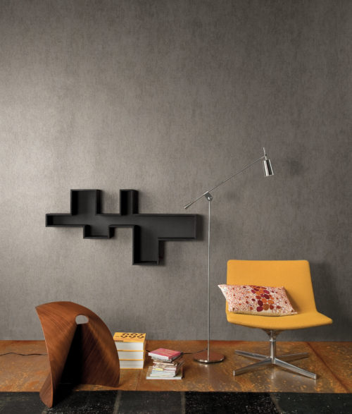 Intérieur contemporain avec une chaise jaune, des objets d'art en bois et des étagères géométriques au mur. Le mur est recouvert d'un revêtement mural gris uni d'aspect béton d'Omexco.