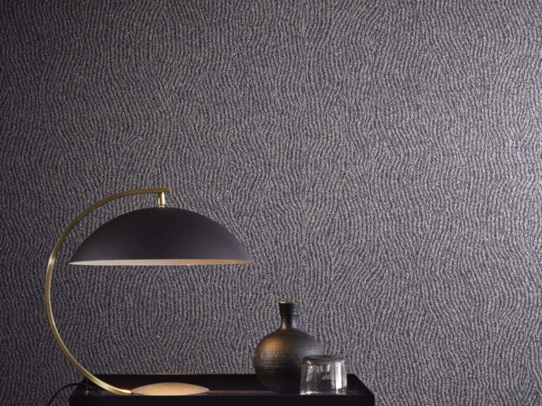 Le revêtement mica de cette photo est imprimé d'un motif géométrique ondulé. Il est associé dans cet intérieur à une lampe et un vase géométriques noirs.