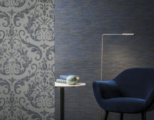 Chambre tactile avec un élégant revêtement mural en damas et un revêtement mural bleu foncé en teinture d'espace. Un siège en velours et une liseuse invitent à la détente. La collection Omexco Elegance.