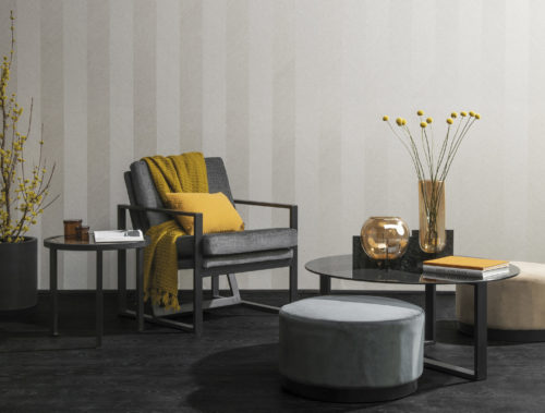Photo d'un mur avec des revêtements muraux en lin Omexco. Table, table d'appoint et chaise longue en fer. Détails jaunes.