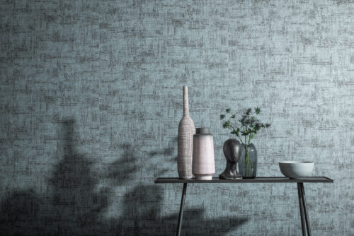 Photo d'intérieur bleu glacier avec table épurée. Sur la table, des vases et un chardon. Ils projettent une ombre sur les revêtements muraux Aruba d'Omexco.