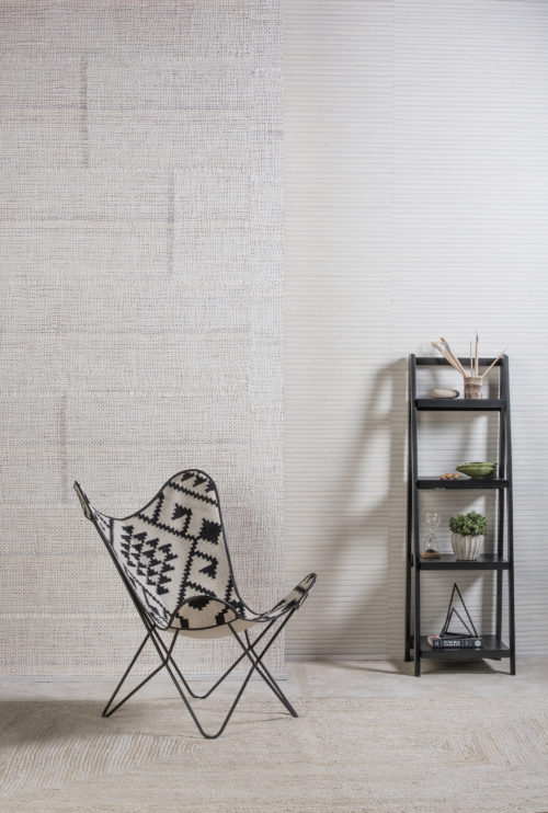 Chaise étonnante en tissu ethnique noir et blanc. Des étagères sur le mur du fond avec des pinceaux, des livres et un sablier.