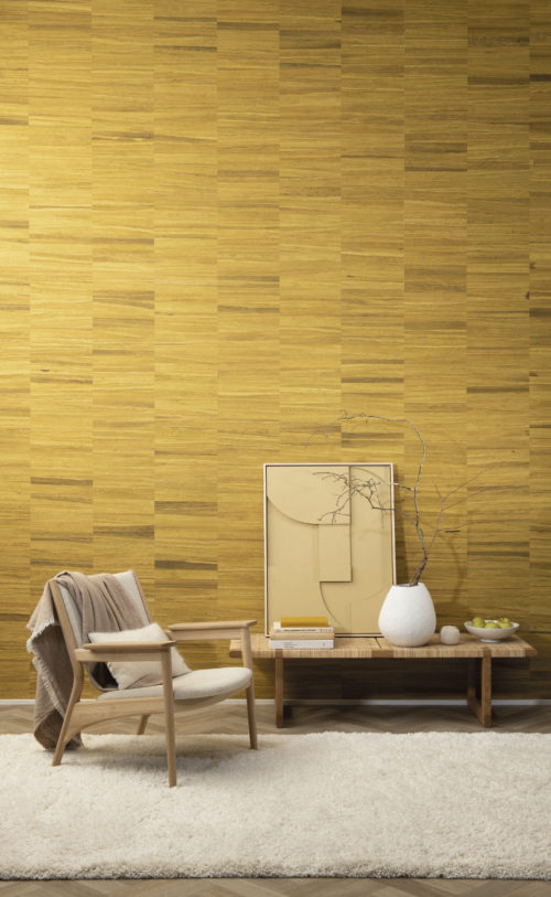 La collection de revêtements muraux Atelier d'Omexco est un hommage tactile à l'importance de l'artisanat dans la décoration d'intérieur. Ici, nous voyons un collage rayé jaune ensoleillé fait à partir d'écorce de bananier, qui est la toile de fond parfaite pour la chaise longue en rotin et la banquette. Si vous êtes à la recherche d'une décoration bohème chic, vous serez certainement inspiré par cette image !