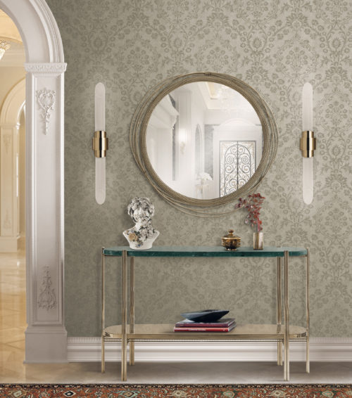 Mur dans un couloir avec un miroir et deux lampes de chaque côté du miroir. Le miroir est décoré de câbles. Console en verre et métal doré. Buste. Revêtement mural en damas sur le mur.