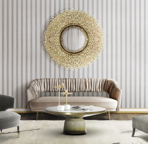 Salon clair avec canapé en velours rose. Le tissu du dossier présente de jolis plis. Au-dessus, un miroir avec des détails en nacre. Revêtement mural Infinity.